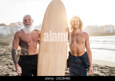 Padre e figlio surfista multigenerazionale che si gode surf sessione di sport estremi in vacanza estiva - Focus su uomo anziano Foto Stock