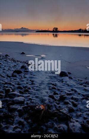 tramonto sulla spiaggia con neve e falò in primo piano Foto Stock