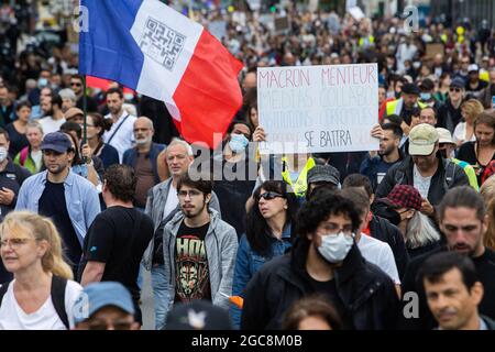 Il manifestante ha un segno Macron Liar, Medias Collabos, Istituzioni corrotte, la gente si batterà da sola durante una giornata nazionale di protesta contro la vaccinazione obbligatoria Covid-19 per alcuni lavoratori e l'uso obbligatorio del certificato sanitario richiesto dal governo francese a Parigi il 7 agosto 2021. Sabato i manifestanti sono scesi per le strade di tutta la Francia per il quarto fine settimana di fila per radunarsi contro un nuovo pass sanitario necessario per entrare in un bar o viaggiare su un treno interurbano, due giorni prima che le nuove regole entrino in vigore. Un pass sanitario valido è generato da due tamponi provenienti da un vaccino riconosciuto Foto Stock