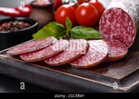 Salame spagnolo di salsiccia secca su fondo di cemento scuro. Preparazione di deliziosi panini freschi Foto Stock