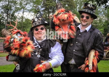 Schiffshebewerk Henrichenburg, Waltrop, Germania, 7 agosto 2021. Due appassionati hanno portato con sé i loro morbidi amici draghi. I fan e i visitatori del Steampunk, molti dei quali in costumi futuristici e costumi a vapore, si riuniscono per il festival ´STeampunk Jubilee Market´ presso lo storico punto di riferimento dell'impianto di risalita di Henrichenburg, parte del parco delle serrature di Waltrop sul canale Dortmund-EMS, oggi museo industriale. La vecchia struttura in ferro, le torri di controllo, le case delle macchine e il museo formano uno sfondo suggestivo per il festival.Credit: Imageplotter/Alamy Live News Foto Stock