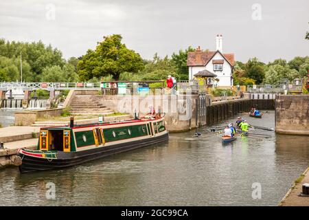 Barca stretta del canale e la gente in barche a remi passando attraverso le serrature sul Tamigi a Goring Oxfordshire Inghilterra Foto Stock