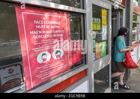 I rivestimenti del viso devono essere indossati segno sull'Ufficio postale con una persona che esce, Abergavenny, Galles, Regno Unito Foto Stock