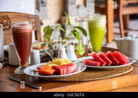 Dieta, insalata di frutta mista biologica sana nel piatto bianco su un tavolo di legno con bel decor e sfondo sfocato - colazione sana, perdita di peso conce Foto Stock