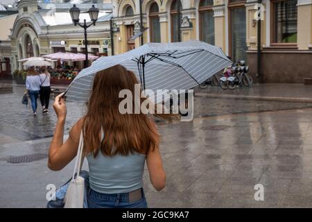 Mosca, Russia. 7 agosto 2021 UNA giovane ragazza con ombrello cammina lungo la via Kuznetsky Most nel centro di Mosca durante la pioggia, in Russia Foto Stock