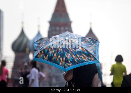 Mosca, Russia. 7 agosto 2021 tempo piovoso a Mosca. Una donna con un ombrello cammina sulla Piazza Rossa sullo sfondo della Cattedrale di San Basilio nel centro di Mosca, Russia Foto Stock