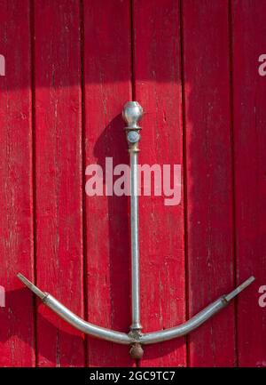 ancorante per navi metalliche, ancora per ornamento, ancora per navi marittime, ancora su porta verniciata di rosso, ancora su sfondo verniciato di rosso, decorazione nautica. Foto Stock