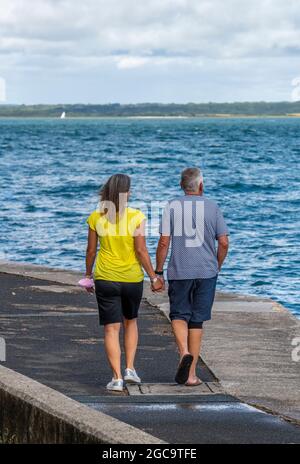 coppia di mezza età, mano in mano, camminando sulla spiaggia, camminando insieme al mare, camminando mano in mano, coppia sposata, amanti più anziani. Foto Stock