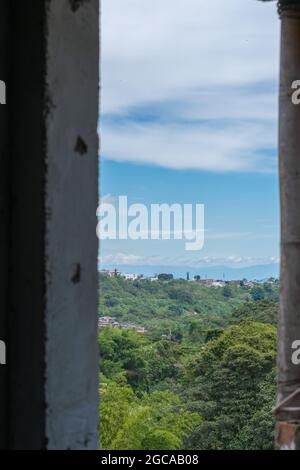 Vista da una finestra l'orizzonte nella città di Pereira-Colombia, con l'incontro di aree urbane e rurali, cielo nuvoloso e clima caldo Foto Stock