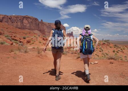 Escursioni il Wildcat Trail nel Monument Valley Navajo Tribal Park, Stati Uniti. Una calda giornata di agosto con cielo blu e scogliere di arenaria, buttes, e pinnacoli. Foto Stock