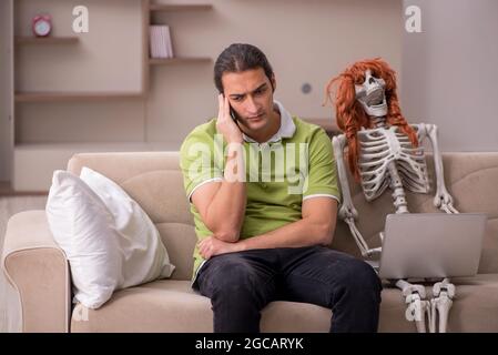 Uomo seduto sul divano con scheletro femminile Foto Stock