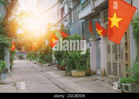 Bandiere lungo una piccola strada in Hanoi. Bandiere nazionali vietnamite in case strette corsie residenziali. Patriottismo dei cittadini durante la celebrazione di Foto Stock