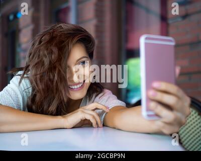 Felice giovane donna sorridente durante la videochiamata online. Incontro online con gli amici. Sorrideva - ha ricevuto una notizia sul cibo. Foto Stock