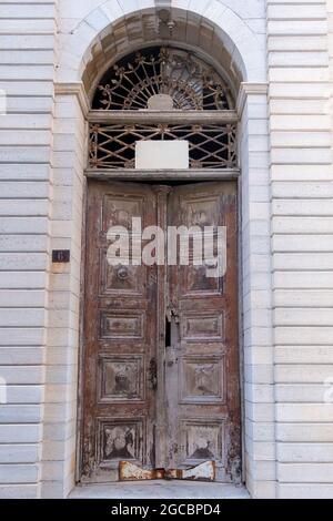 Porta aperta a metà in legno ornamentale marrone con arrugginita trama metallica. Facciata di marmo muro tradizionale neoclassico edificio vintage porta età Foto Stock