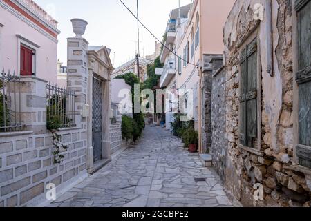 Destinazione turistica estiva isola di Syros Grecia. Vuoti acciottolati vicolo case in pietra con colorate bouganville con piante fresche. WA Foto Stock