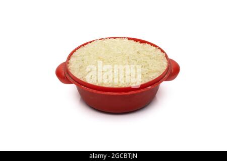 Riso secco non cotto su una piccola ciotola rossa sporca su uno sfondo bianco isolato Foto Stock