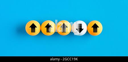 Icone freccia sulle palle da tennis da tavolo in fila con una che si sposta verso il basso mentre altre si muovono verso l'alto. Concetto di innovazione, individualità, differenza o diversità Foto Stock