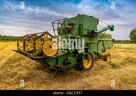 Vecchia mietitrebbia su un campo di grano con cielo blu Foto Stock