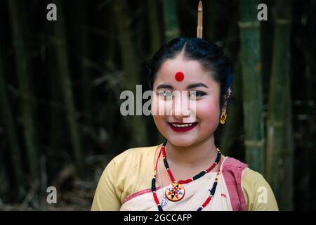 ragazza sorridente faccia isolata vestita tradizionale in festa con immagine di sfondo sfocata è presa in occasione del bihu ad assam india. Foto Stock