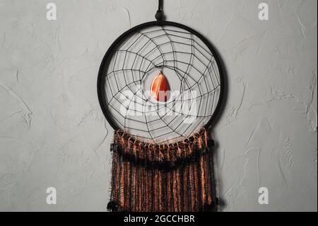 Dream catcher con fili arancioni neri su fondo di cemento Foto Stock