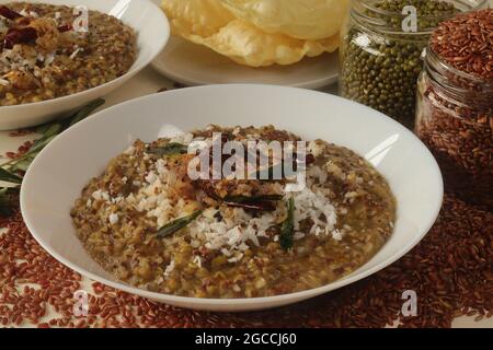 Porridge o gruel a base di riso Navara, fagioli mungs e semi di fieno cosparsi di cocco fresco grattugiato. Conosciuto anche come navara kichadi o uluva kanji Foto Stock