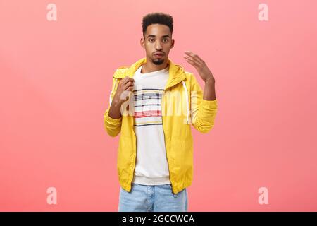 Ragazzo vestito in modo inappropriato per il tempo caldo sudare respirare e fare vento con palmo scosso per raffreddare giù il collare di t-shirt mentre Foto Stock