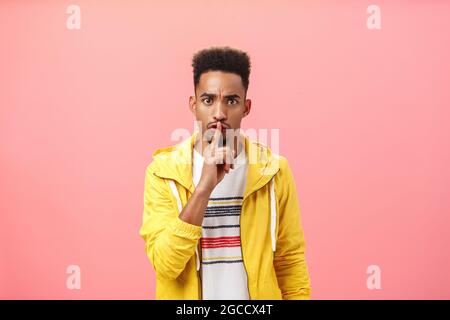 Promessa dire a nessuno che è segreto. Stretto e grave arrabbiato intenso africano americano ragazzo con acconciatura afro schiumare a macchina fotografica con pinna indice Foto Stock