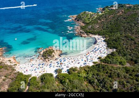 Vista dall'alto, splendida vista aerea di una spiaggia di sabbia bianca piena di ombrelloni e persone che nuotano in un'acqua turchese. Foto Stock
