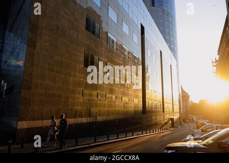 Bucarest, Romania - 7 agosto 2021: La gente cammina vicino a un alto edificio di vetro al crepuscolo nel centro storico di Bucarest. Foto Stock