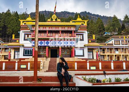 giovane ragazza seduta di fronte all'antico monastero buddista colorato al giorno immagine è presa al monastero di bomdilla arunachal pradesh india. Foto Stock