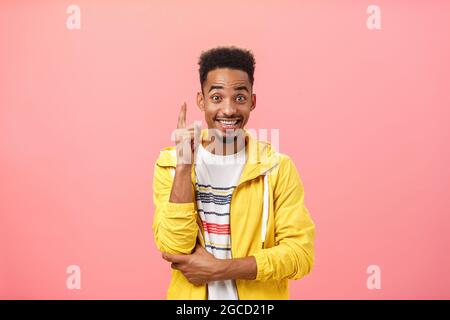 Entusiasta ragazzo afroamericano compiaciuto aggiungendo suggerimento alzando il dito indice in eureka gesto e sorridendo gioiosamente mentre discutere interessante Foto Stock