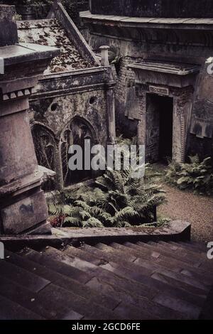 Tombe in stile neogotico vittoriano con felci che crescono nello storico cimitero londinese Foto Stock