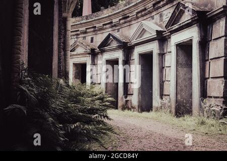 Mausoleo del cimitero vittoriano con architettura classica e vegetazione ricoperta Foto Stock
