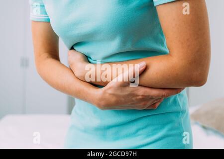 Donna caucasica che soffre di mal di stomaco a casa. Foto Stock