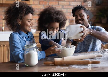 Felice famiglia etnica con figlia che si cuoce insieme a casa Foto Stock