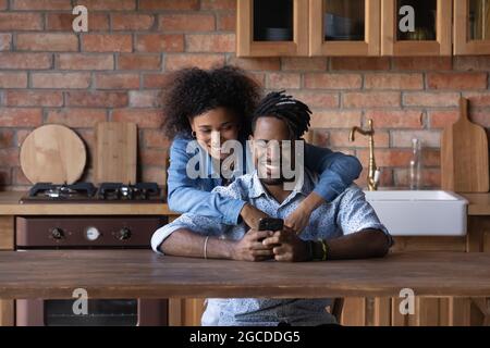 Sorridente giovane coppia biraciale usare il cellulare insieme Foto Stock