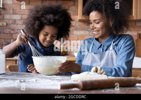 Felice madre biraciale e teen figlia cucinare insieme Foto Stock