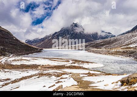 le montagne del cappuccio della neve con il lago congelato e il cielo blu luminoso alla mattina dall'angolo piatto l'immagine è presa a sela tawang arunachal pradesh india. Foto Stock