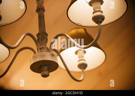 Lampade luminose con sfumature di tessuto sono illuminate su un elegante e bellissimo lampadario in serata, a creare un'atmosfera accogliente. Un motel. Foto Stock