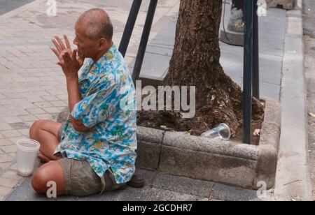 Uomo che prega sul marciapiede si Lom Road Sala Daeng Bangkok Thailandia Foto Stock