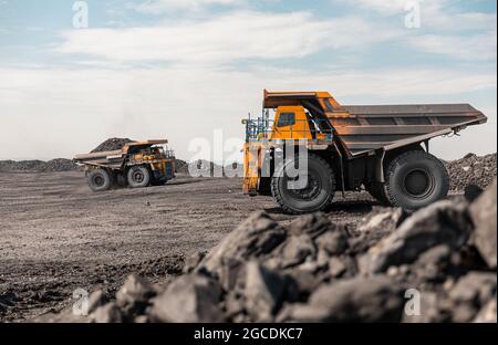 Dumper da cava di grandi dimensioni. Grande dumper da miniera giallo sul luogo di lavoro. Caricamento del carbone nel camion della carrozzeria. Produzione di minerali utili. Macchinari per attività estrattive di autocarri Foto Stock