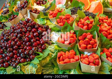 Ciliegie e fragole in vendita presso una bancarella di mercato Foto Stock