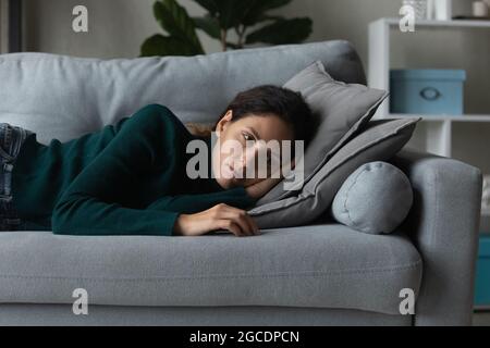 Primo piano donna frustrata che si stesa sul divano da sola, sentendosi depressa Foto Stock