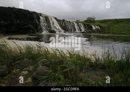 una grande cascata su un corpo d'acqua Foto Stock