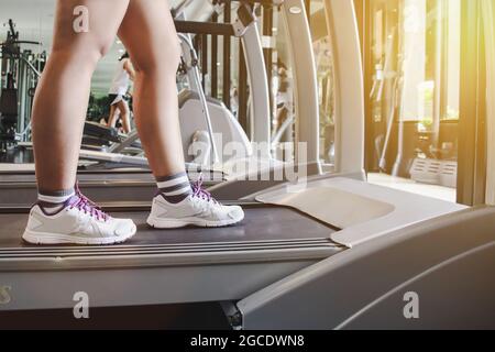 Primo piano scarpe donna che corre sul tapis roulant. Donna con gambe muscolari in palestra Foto Stock