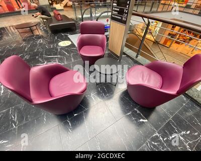 Oberhausen, Germania - 9 luglio. 2021: Vista su tre divani in pelle lilla pavimento in marmo omn intorno a un piccolo tavolo nero nella zona di riposo del centro commerciale Foto Stock