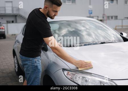 Mano di uomo pulisce il faro della sua auto usando il tappeto. Autolavaggio self-service. All'aperto Foto Stock