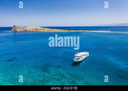 Vista aerea di nuotatori e snorkeling intorno a una barca in un oceano cristallino e blu in estate (Creta, Grecia) Foto Stock