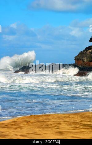 Big splash è creato come una potente onda colpisce le rocce sulla spiaggia di Lumahaa'i sulla Kauai, Hawaii. Foto Stock