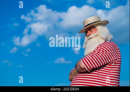 Un uomo anziano in un costume da bagno classico cammina lungo la spiaggia in una calda giornata estiva Foto Stock